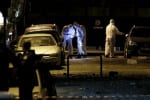 Forensic experts search for evidence on a street where a bomb exploded outside the entrance of the Hellenic Business Federation offices in Athens