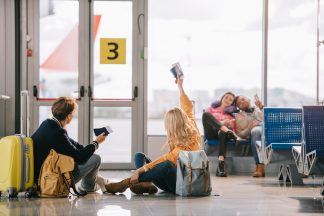 young travelers with passports and boarding passes greeting each other in airport terminal